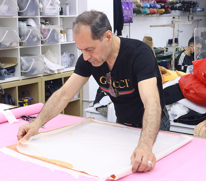 Zouhir Karsli measures fabric and pattern paper on an NYC Garment district table.